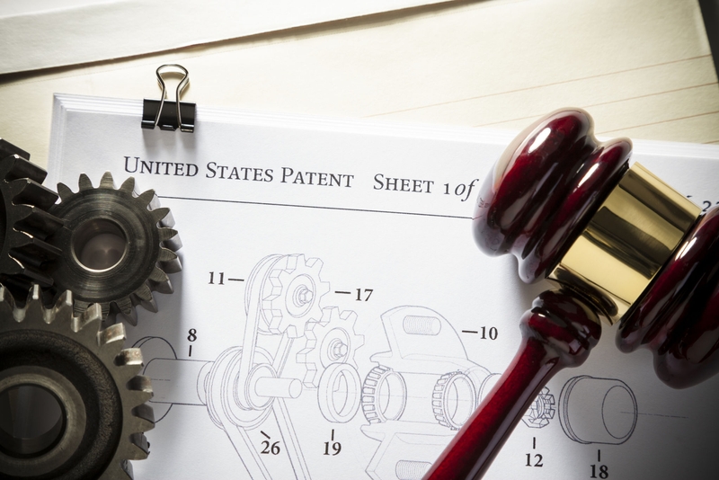 Gavel next to gears and mechanical diagram for patent application.